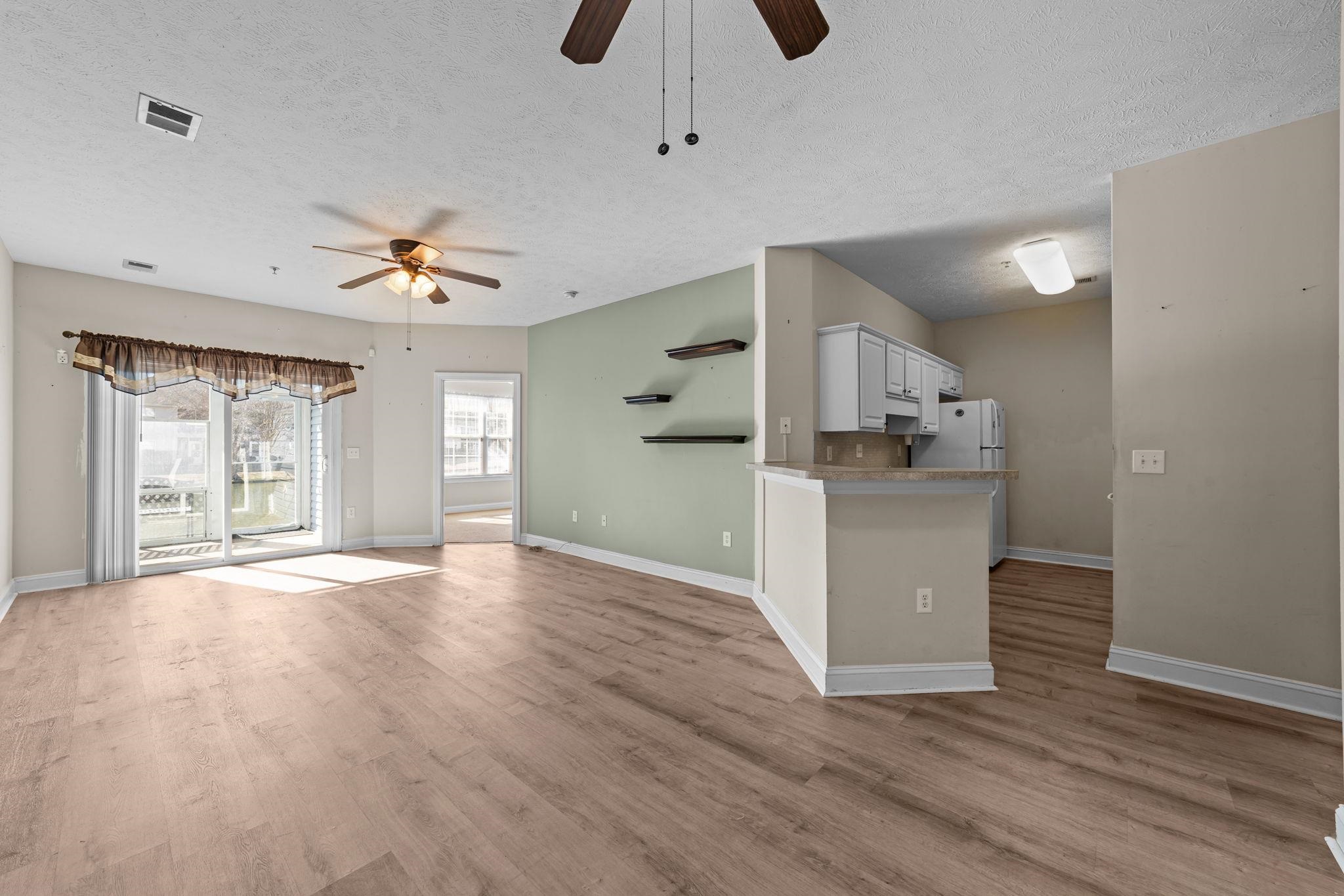 120 Fountain Pointe Lane, Unit 103 Myrtle Beach, SC 29579 - Photo 11 of 26 Unfurnished living room with ceiling fan, a textured ceiling, and light wood-style floors
