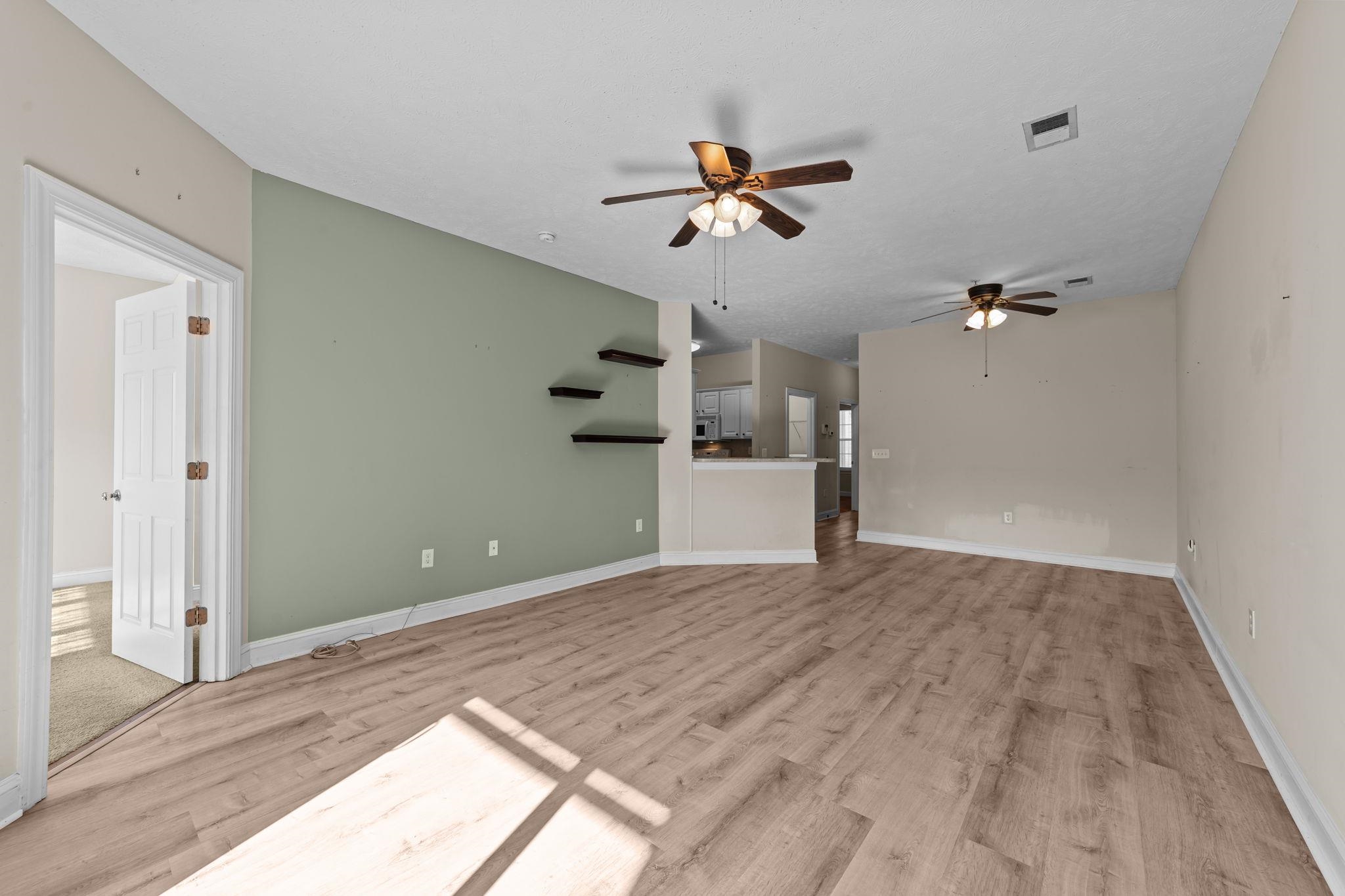 120 Fountain Pointe Lane, Unit 103 Myrtle Beach, SC 29579 - Photo 12 of 26 Unfurnished living room featuring a ceiling fan and light wood finished floors