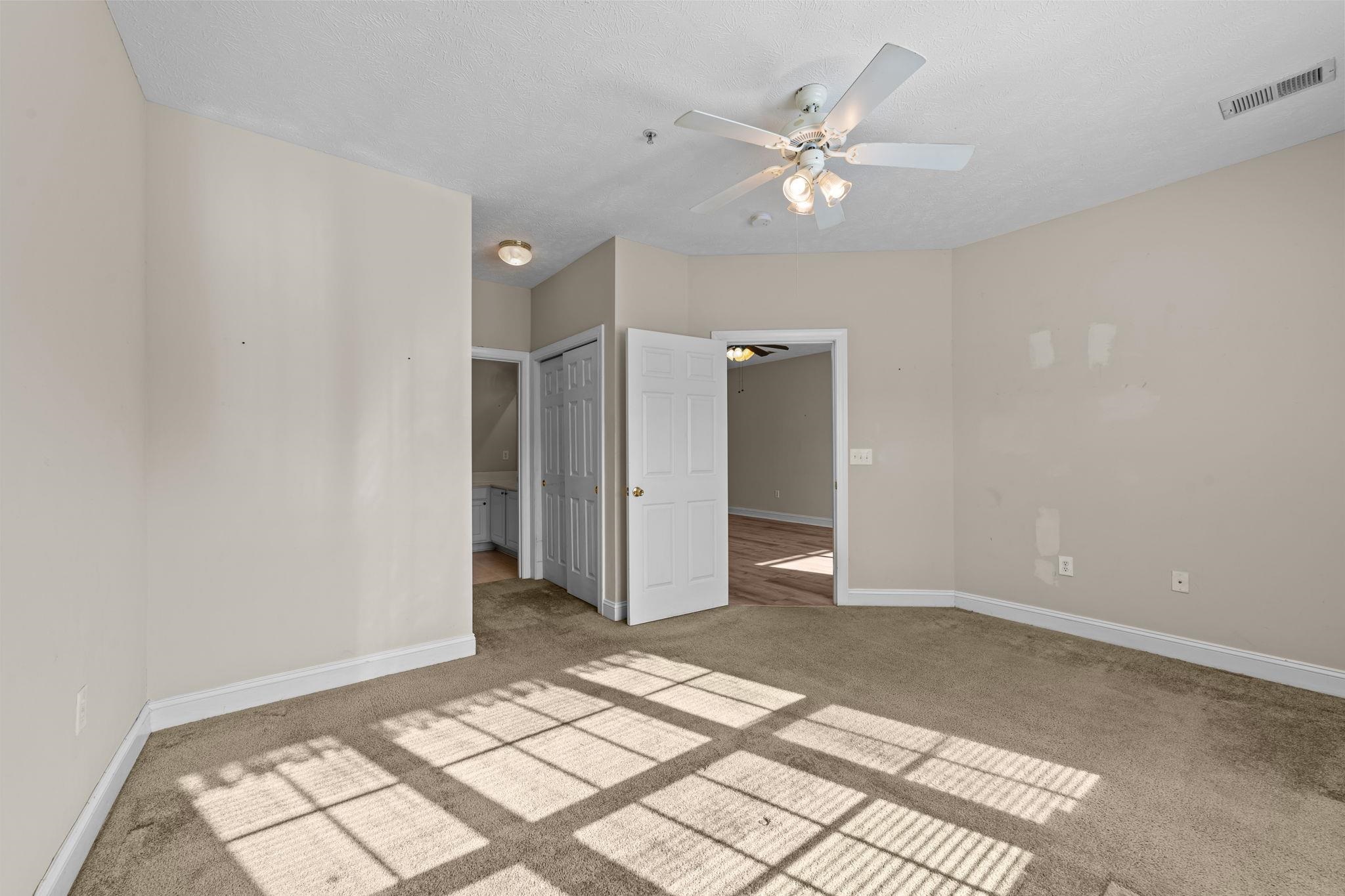 120 Fountain Pointe Lane, Unit 103 Myrtle Beach, SC 29579 - Photo 14 of 26 Unfurnished bedroom with ensuite bath, carpet, ceiling fan, and a closet