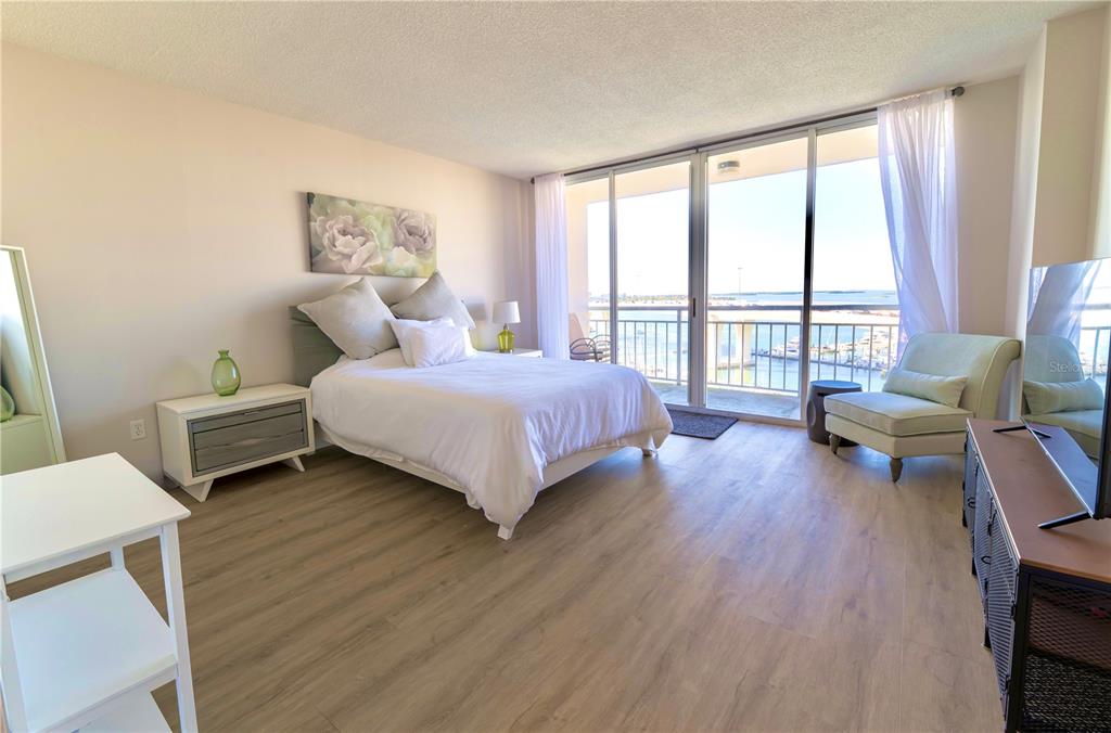 100 Pierce Street, Unit 1102 Clearwater, FL 33756 - Photo 13 of 45 a bedroom with a bed a large window and wooden floor