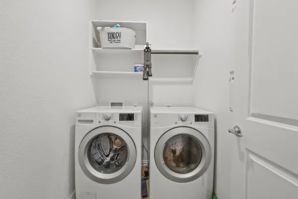 a utility room with dryer washer and a view of kitchen