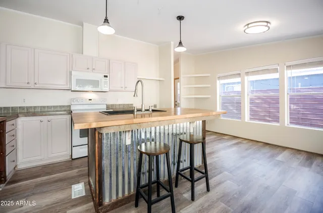 a kitchen with stainless steel appliances granite countertop a stove a sink a refrigerator and wooden floor