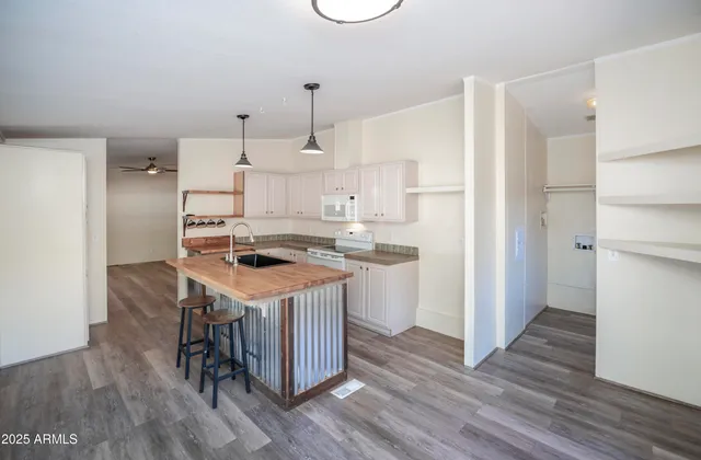 a kitchen with a sink a refrigerator a stove and white cabinets with wooden floor
