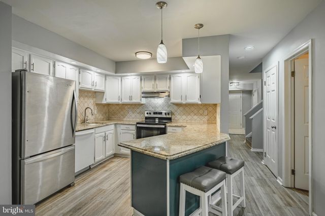 a kitchen with a refrigerator a sink and wooden floor