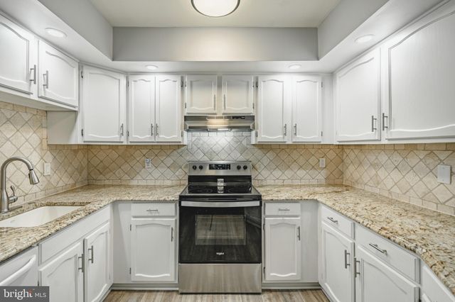 a kitchen with granite countertop a stove sink and cabinets