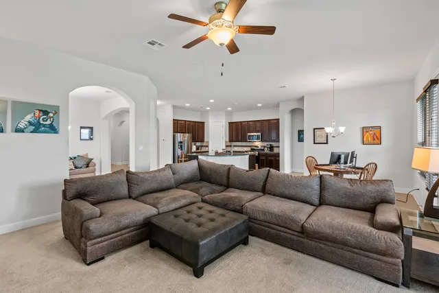 a living room with furniture kitchen view and a chandelier