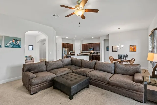 a living room with furniture kitchen view and a chandelier