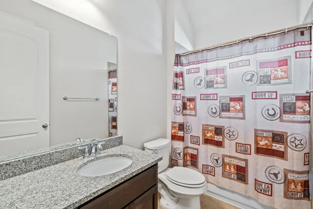 a bathroom with a granite countertop toilet sink and a mirror