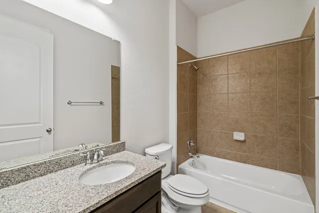 a bathroom with a granite countertop bathtub shower sink mirror vanity and a toilet