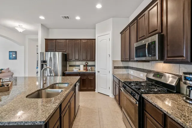 a kitchen with granite countertop a sink stainless steel appliances and cabinets