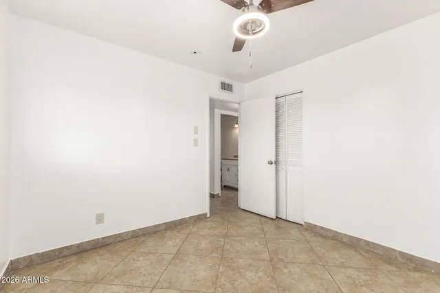 an empty room with a ceiling fan and carpet