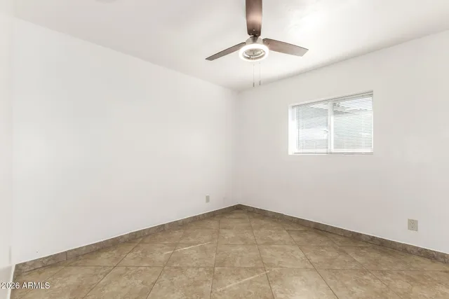 an empty room with a chandelier fan and windows