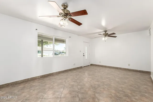 an empty room with windows and fan