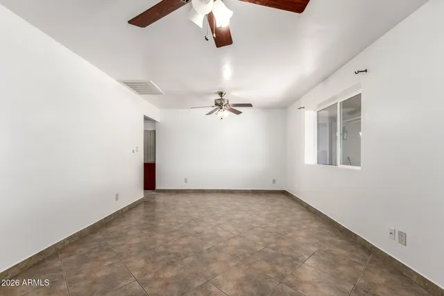 an empty room with windows and fan
