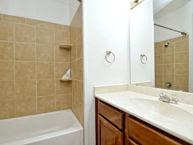 a bathroom with a granite countertop sink a mirror and a bathtub