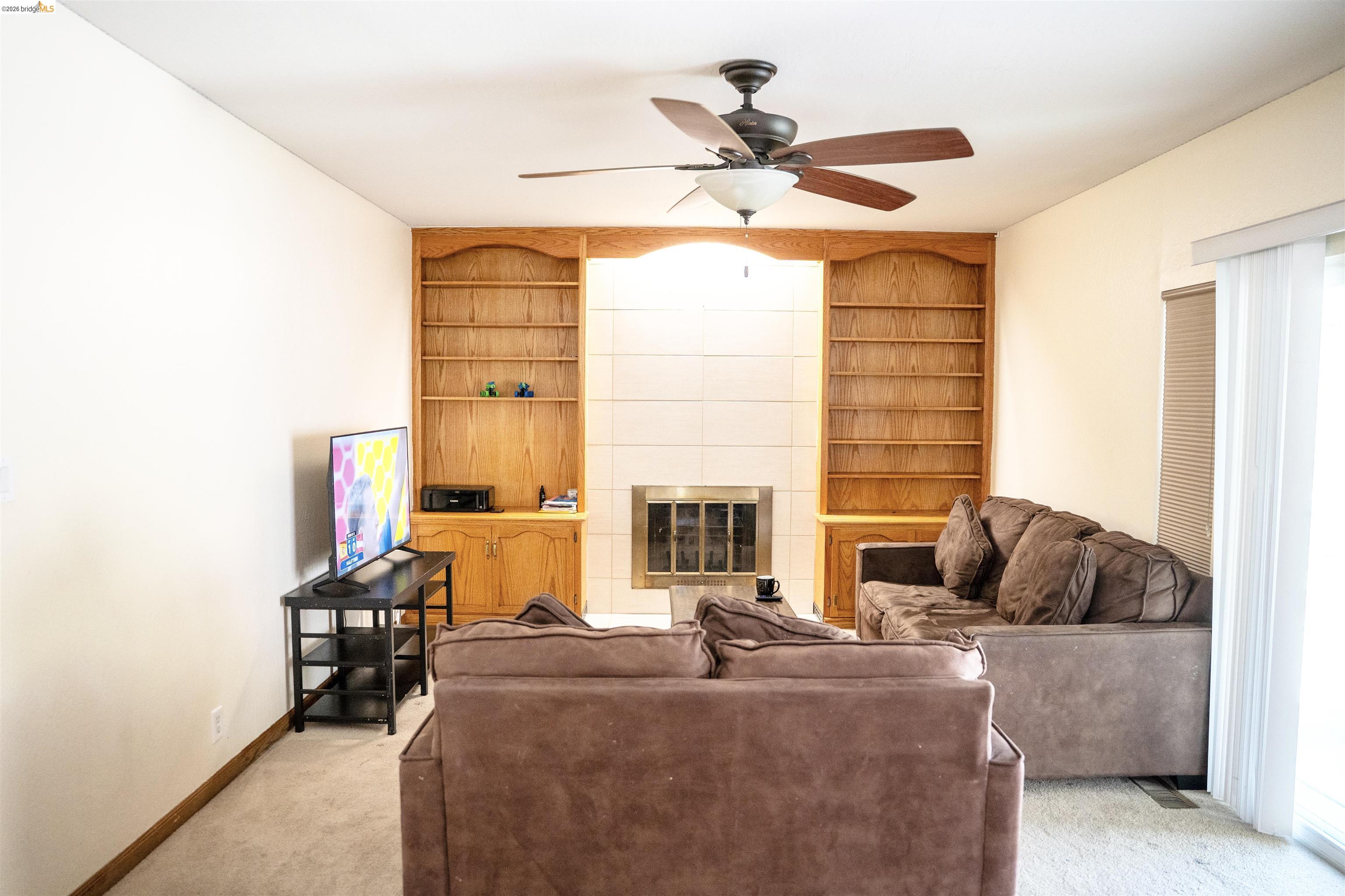 3513 Rio Grande Drive Antioch, CA 94509 - Photo 10 of 22 Living area featuring a fireplace with a tiled surround, integrated wood shelving, and built-in cabinetry