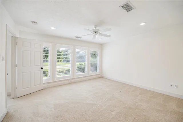 an empty room with chandelier fan and windows