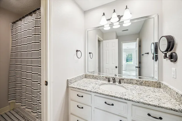 a bathroom with a granite countertop sink a mirror and shower