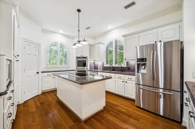 a kitchen with stainless steel appliances granite countertop a refrigerator a stove a sink and white cabinets