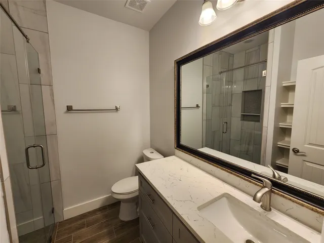 a bathroom with a granite countertop sink a toilet and shower