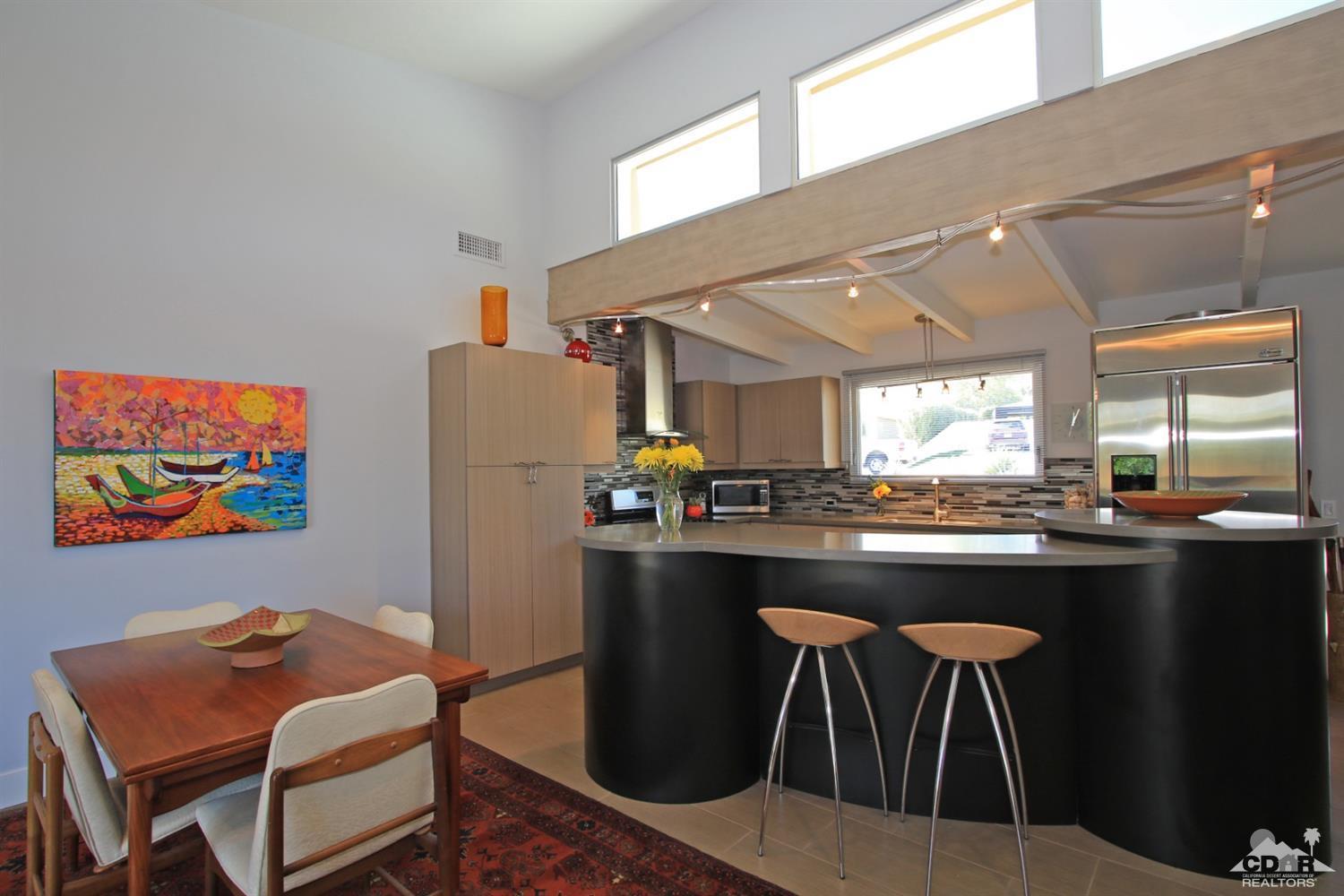 71728 Tunis Road Rancho Mirage, CA 92270 - Photo 12 of 44 a kitchen with stainless steel appliances granite countertop a table chairs in it and wooden floors