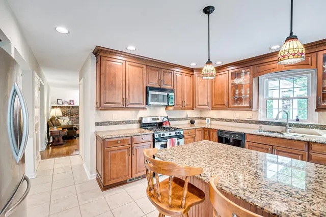 a kitchen with stainless steel appliances granite countertop a stove a sink dishwasher and wooden cabinets with wooden floor