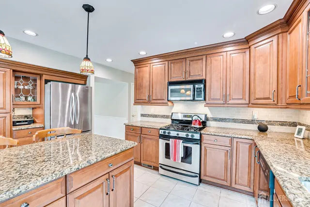 a kitchen with granite countertop a stove a sink and a dining table with chairs