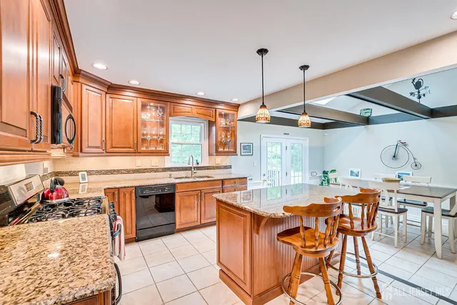 a kitchen with stainless steel appliances granite countertop a stove top oven a sink a dining table and chairs with wooden floor