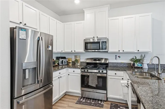 a kitchen with stainless steel appliances granite countertop a refrigerator sink and stove