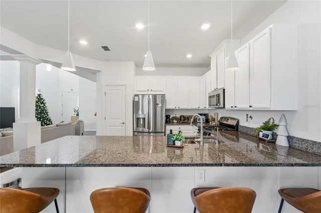 a kitchen with granite countertop a sink a stove a counter space and cabinets