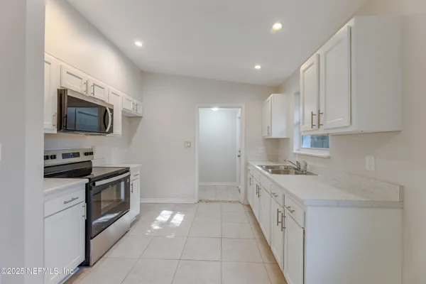 a kitchen with granite countertop a sink a stove top oven and stainless steel appliances