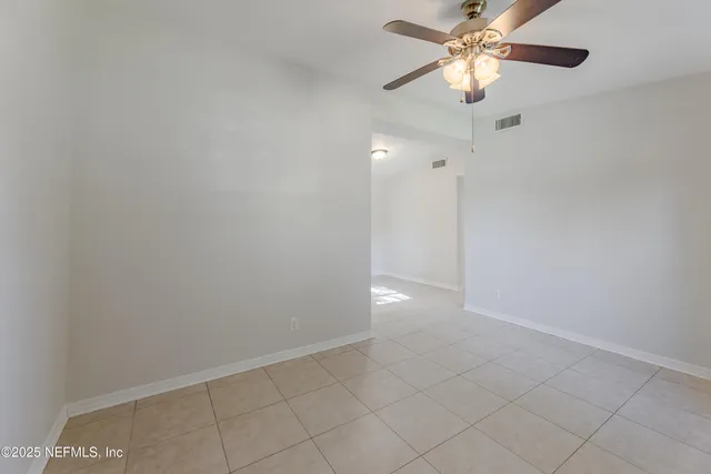 a view of an empty room and chandelier fan