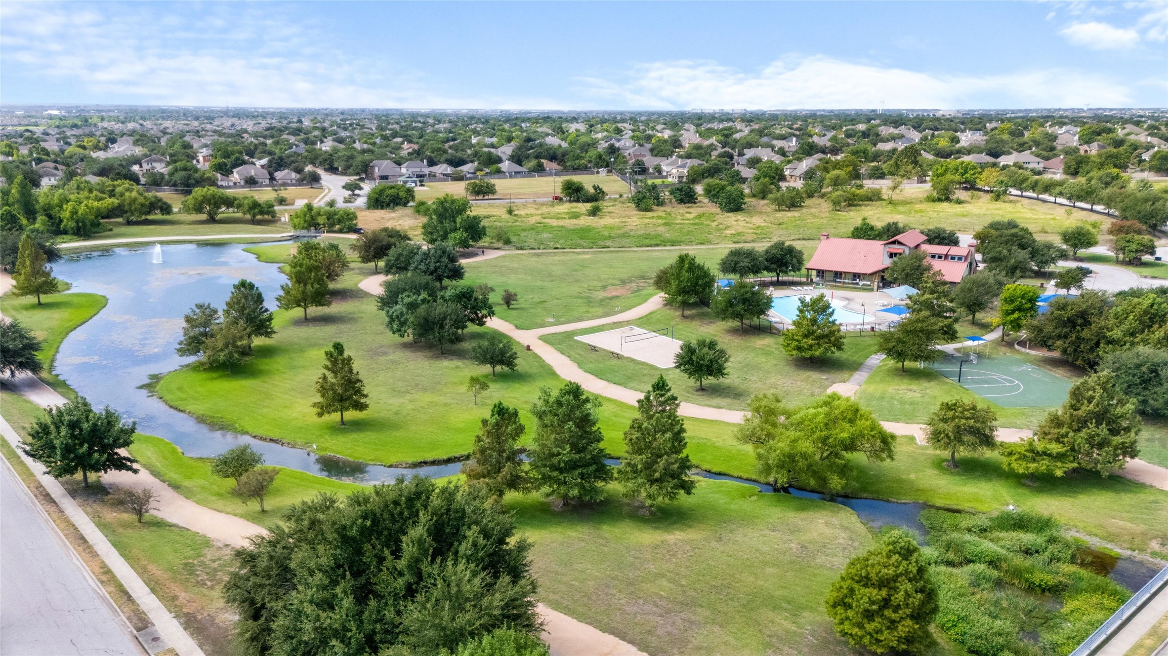 20704 Windmill Ridge Street Pflugerville, TX 78660 - Photo 32 of 34 An aerial perspective reveals a vibrant community with a winding lake, recreational amenities, and verdant green spaces.