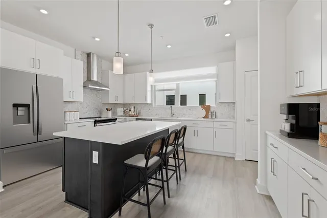 a kitchen with stainless steel appliances kitchen island granite countertop a sink a stove a refrigerator and island with wooden floor