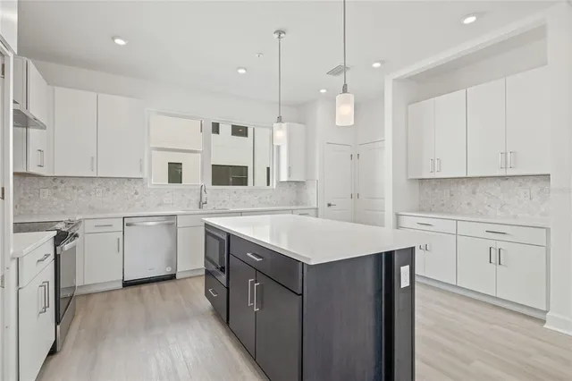 a kitchen with a sink dishwasher and white cabinets with wooden floor