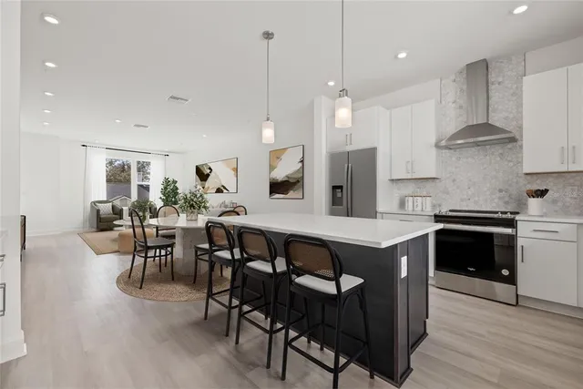 a kitchen with stainless steel appliances granite countertop a stove a sink a refrigerator and a dining table with wooden floor