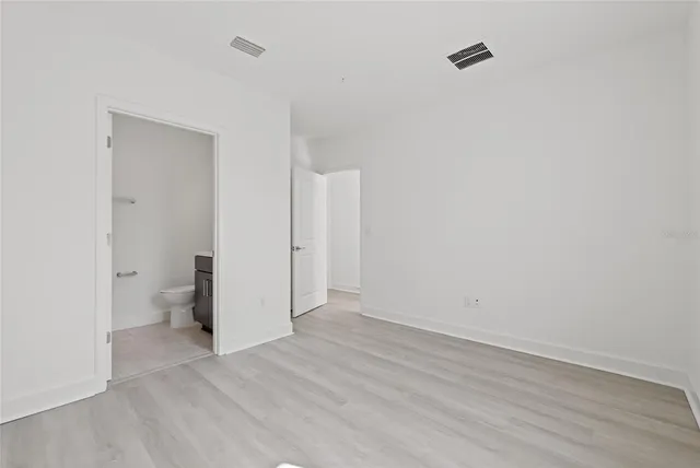 a view of an empty room with wooden floor and a toilet