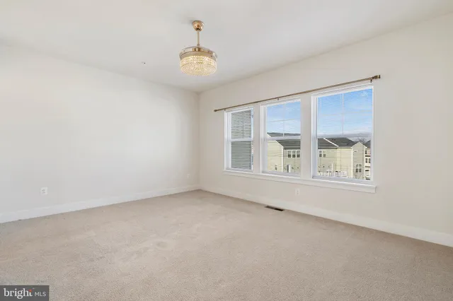 an empty room with chandelier and windows