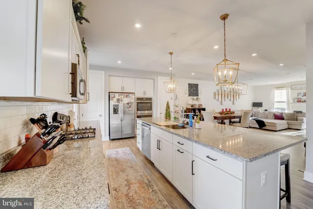 a kitchen with stainless steel appliances kitchen island granite countertop a sink and a refrigerator