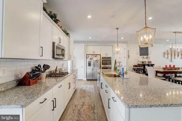 a kitchen with stainless steel appliances granite countertop a sink a stove and a wooden floors