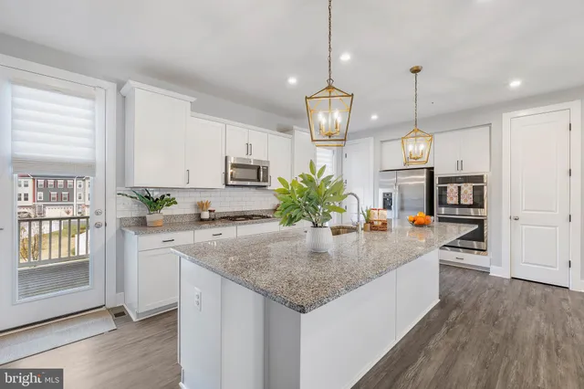 a kitchen with granite countertop stainless steel appliances a white counter top space cabinets and a potted plant