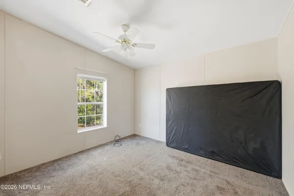 an empty room with windows and fan