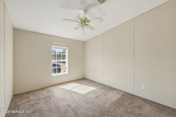 an empty room with windows and fan