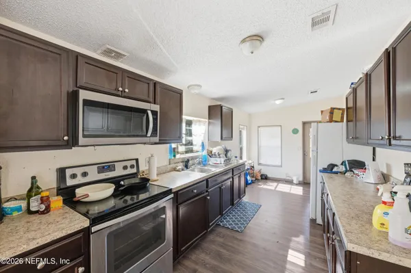 a kitchen with a refrigerator a stove and a wooden floor