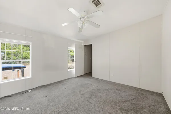an empty room with windows and fan
