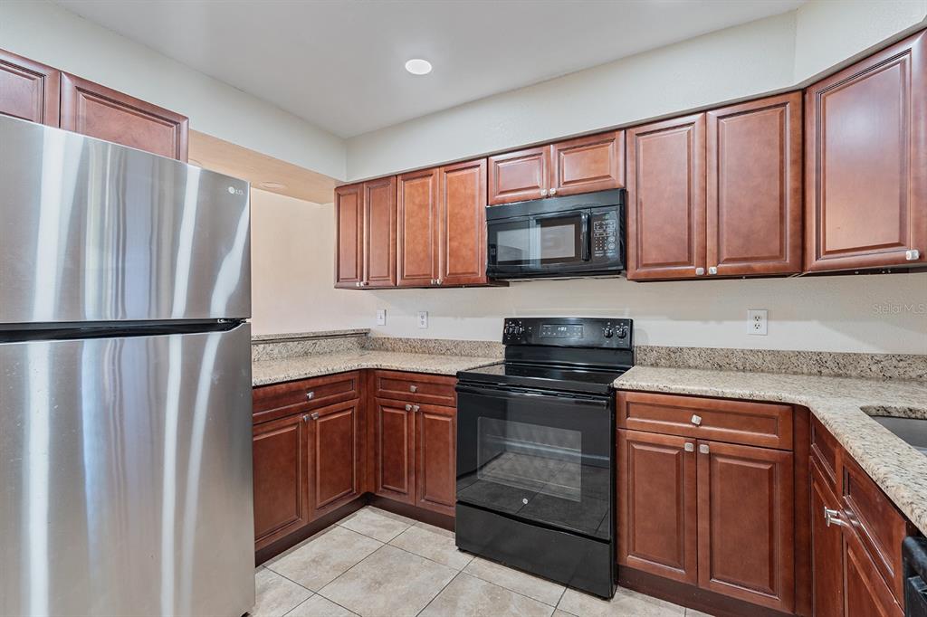 940 Douglas Avenue, Unit 158 Altamonte Springs, FL 32714 - Photo 4 of 23 a kitchen with granite countertop wooden cabinets stainless steel appliances and a window