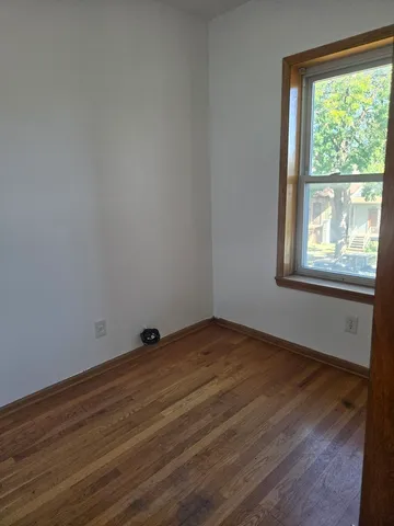 a view of an empty room with wooden floor and window