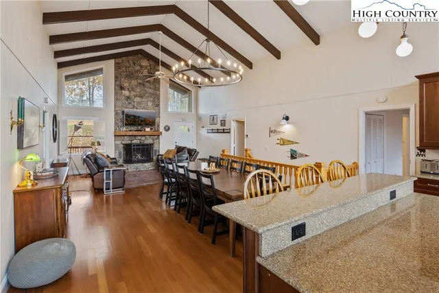 a kitchen with stainless steel appliances granite countertop a dining table chairs refrigerator and sink