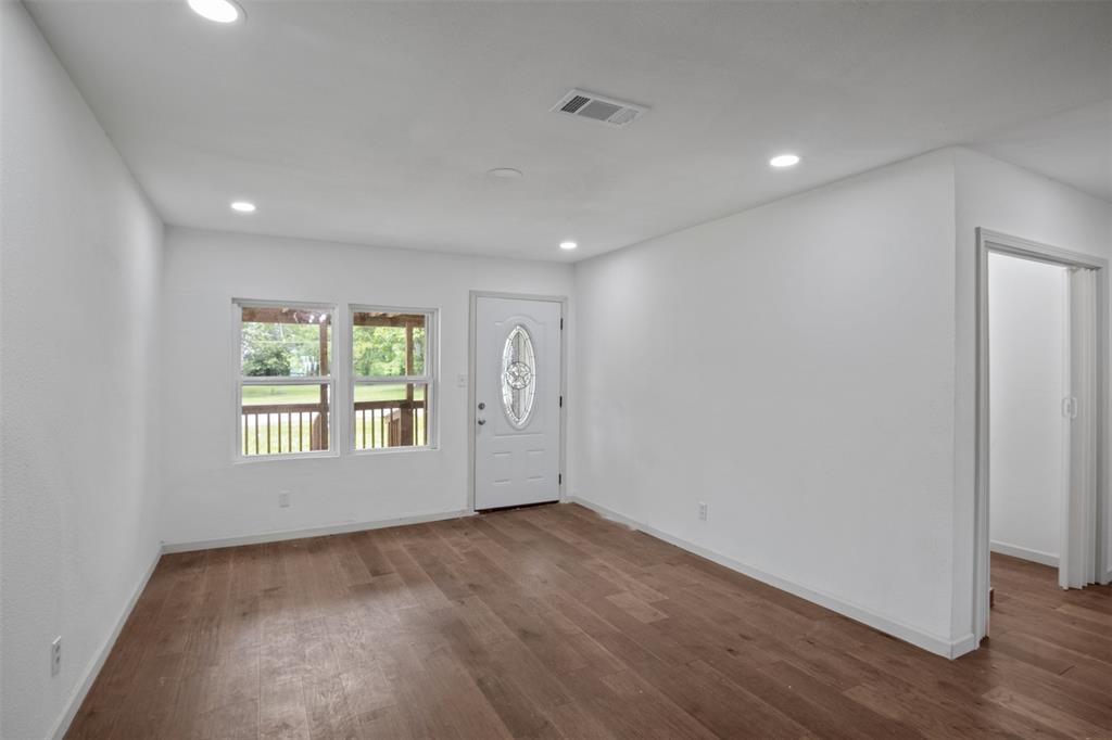 121 Circle Drive Bogata, TX 75417 - Photo 3 of 14 an empty room with wooden floor and windows