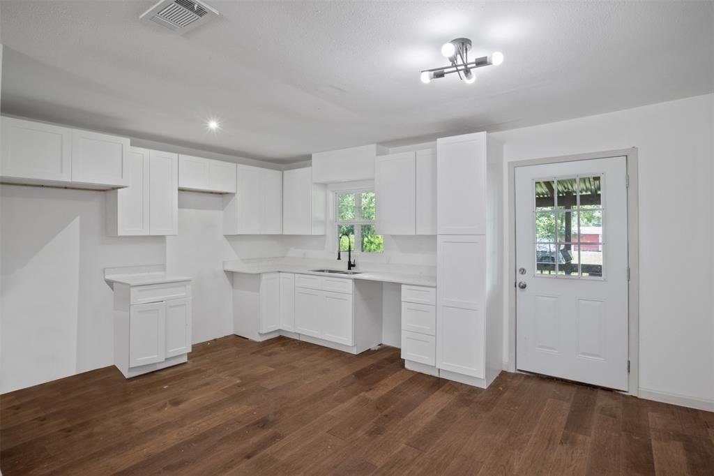 121 Circle Drive Bogata, TX 75417 - Photo 4 of 14 a kitchen with white cabinets and wooden floor